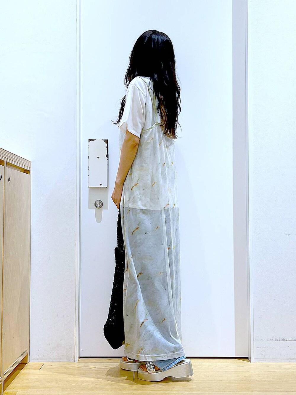 ブルー系のデニムパンツ、ブラック系のトートバッグ、ホワイト系のTシャツ/カットソーを着用したレディースの夏コーディネートの3枚目の写真