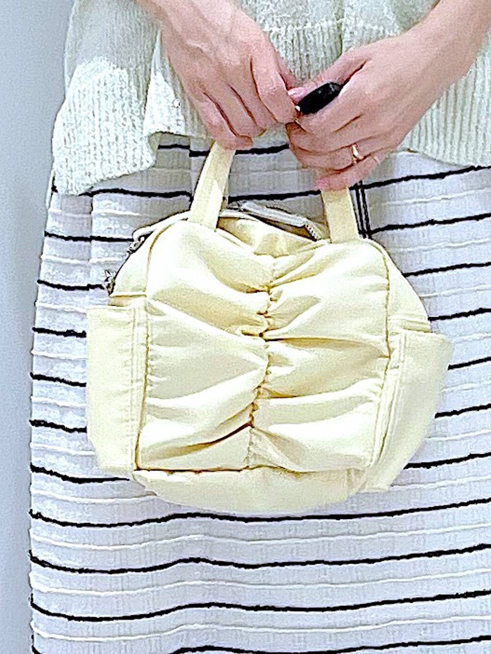 ブラック系のサンダル、イエロー系のショルダーバッグ、ホワイト系のスカートを着用したレディースの夏コーディネートの9枚目の写真