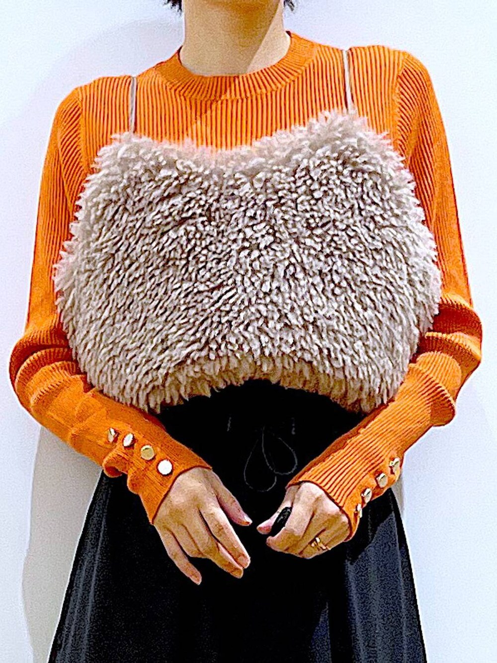 オレンジ系のニット/セーター、ブラウン系のベスト、ブラック系のハンドバッグを着用したレディースの秋コーディネートの7枚目の写真