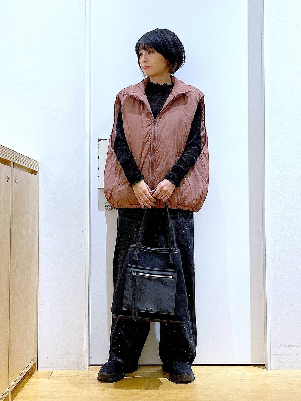 ブラウン系のベスト、ブラック系のトートバッグ、ブラック系のTシャツ/カットソーを着用したレディースの秋コーディネートの2枚目の写真