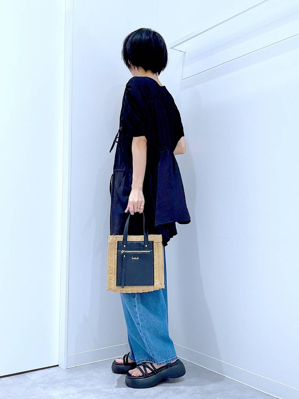 ブルー系のデニムパンツ、ベージュ系のショルダーバッグ、ブラック系のサンダルを着用したレディースの夏コーディネートの3枚目の写真