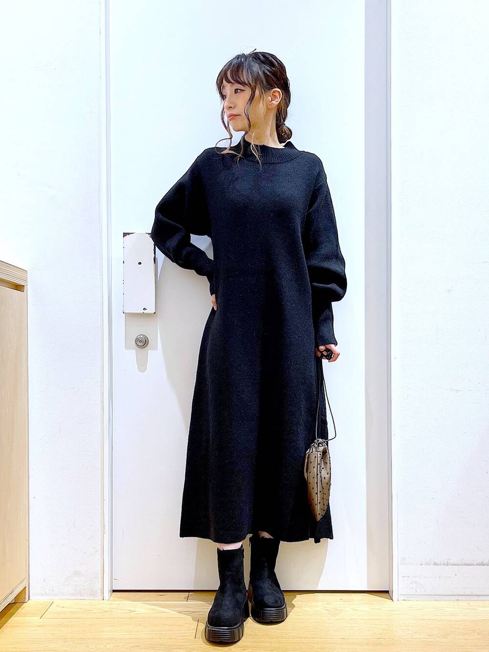 ブラック系のブーツ、ブラック系のワンピース、その他のポーチを着用したレディースの冬コーディネートの2枚目の写真