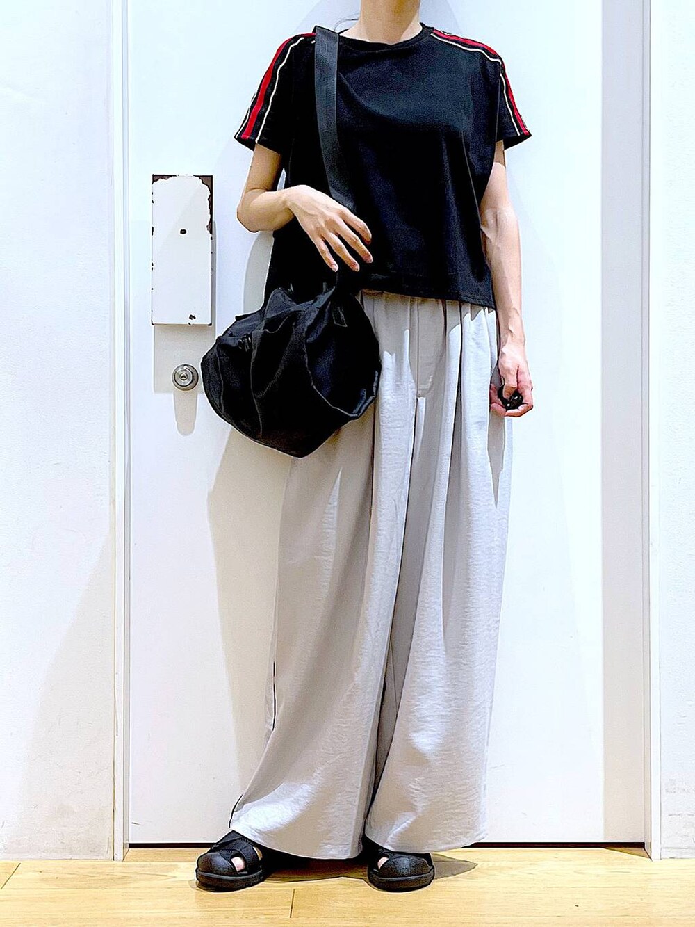 ブラック系のショルダーバッグ、ブラック系のスリッポン、ブラック系のTシャツ/カットソーを着用したレディースの春コーディネートの6枚目の写真