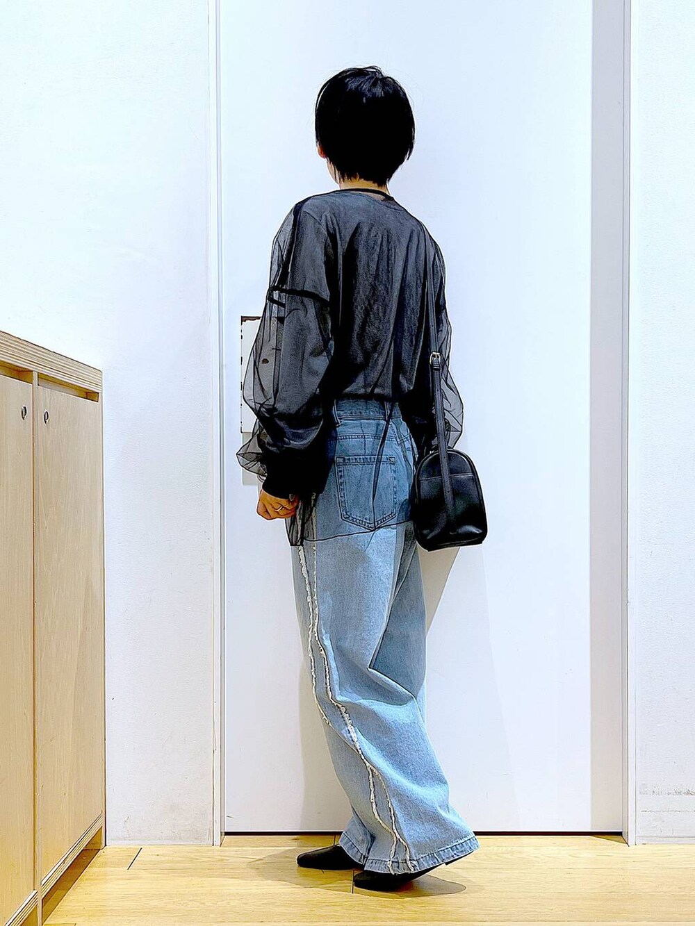 ブラック系のショルダーバッグ、ブラック系のパンプス、ブルー系のデニムパンツを着用したレディースの春コーディネートの3枚目の写真