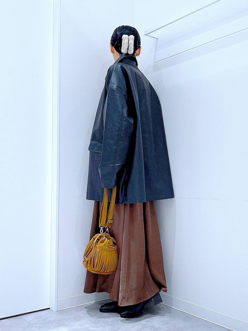 ブラック系のステンカラーコート、レッド系のニット/セーター、ブラック系のブーツを着用したレディースの冬コーディネートの3枚目の写真