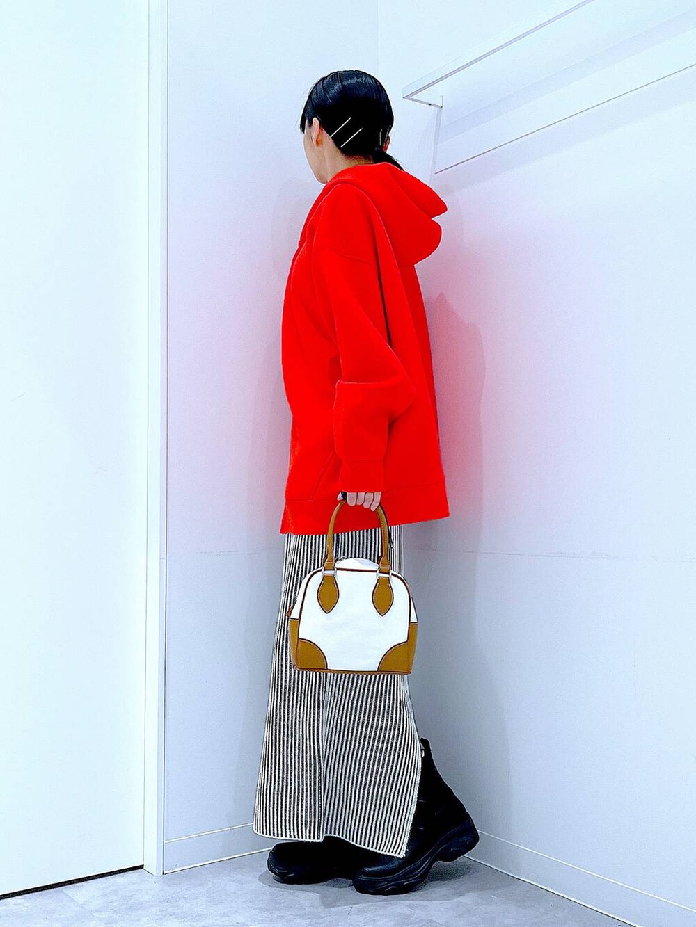 ブラック系のブーツ、ベージュ系のスカート、ホワイト系のハンドバッグを着用したレディースの秋コーディネートの3枚目の写真