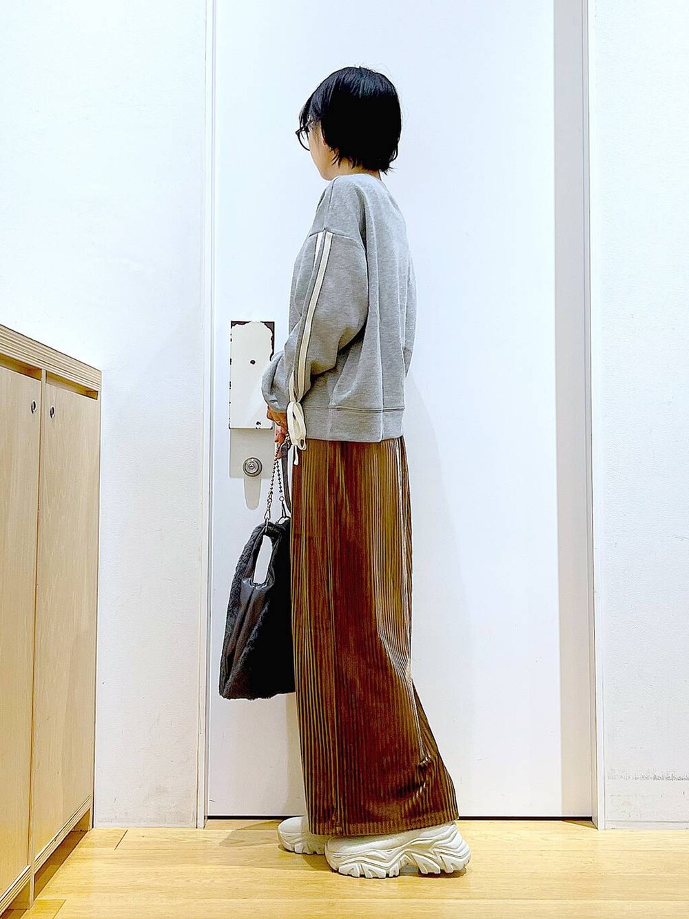 グレー系のショルダーバッグ、ブラウン系のスカート、ベージュ系のブーツを着用したレディースの秋コーディネートの3枚目の写真