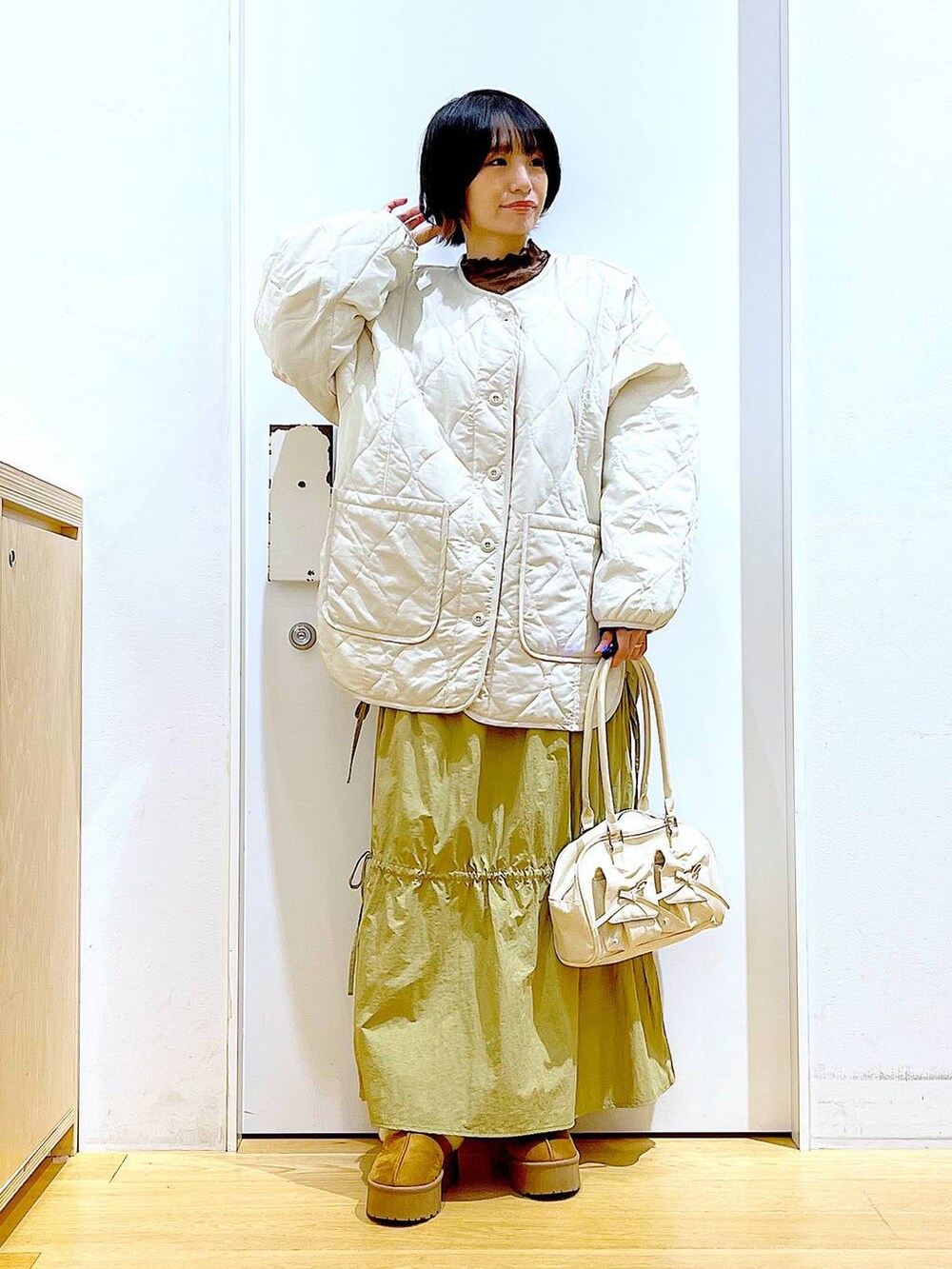 ベージュ系のブルゾン、ベージュ系のスリッポン、ホワイト系のハンドバッグを着用したレディースの秋コーディネートの2枚目の写真