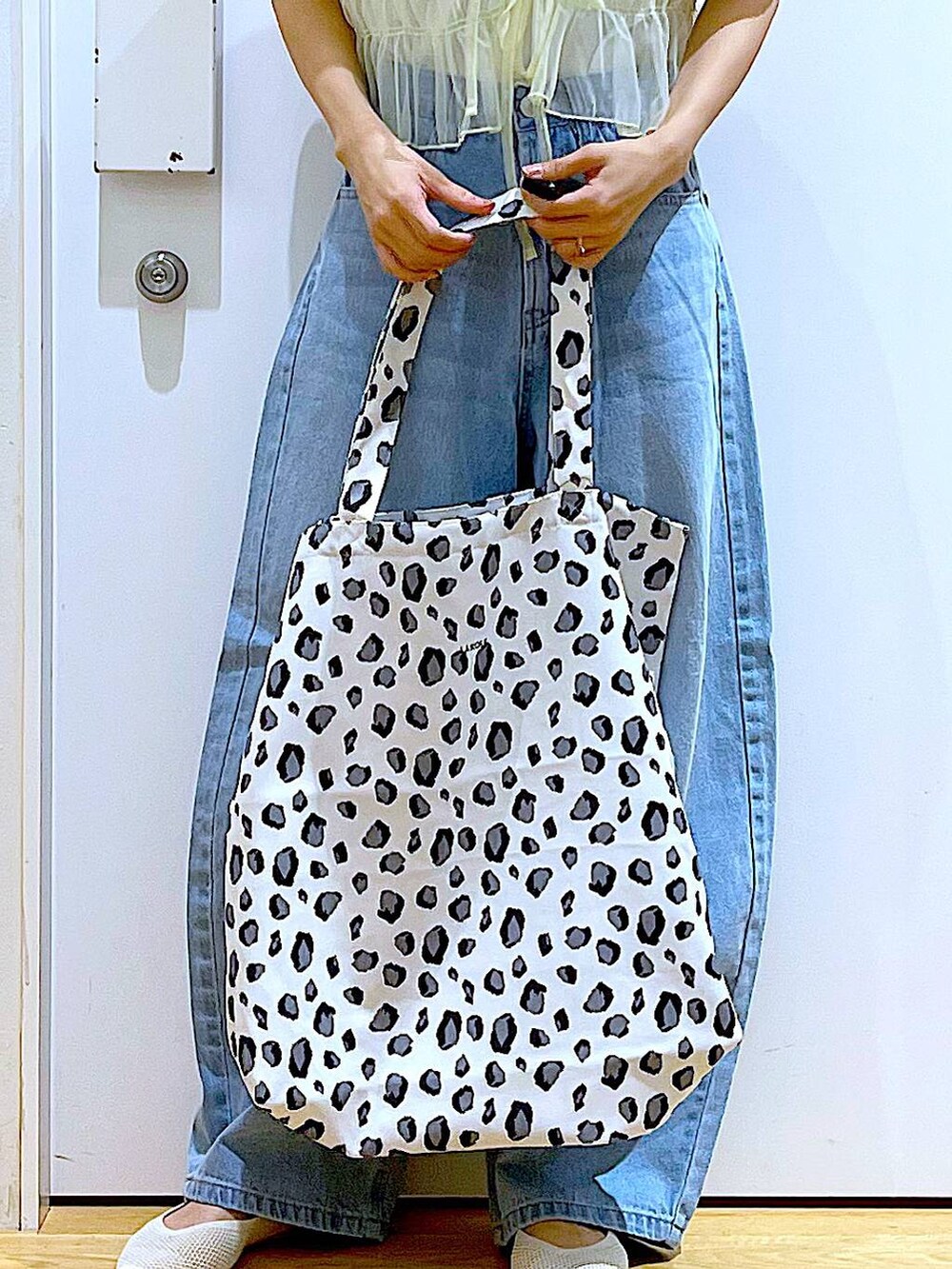 ブルー系のデニムパンツ、イエロー系のキャミソール、ホワイト系のトートバッグを着用したレディースの春コーディネートの9枚目の写真