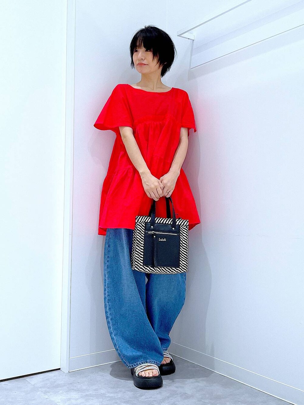 ブルー系のデニムパンツ、ブラック系のショルダーバッグ、シルバー系のサンダルを着用したレディースの夏コーディネートの2枚目の写真