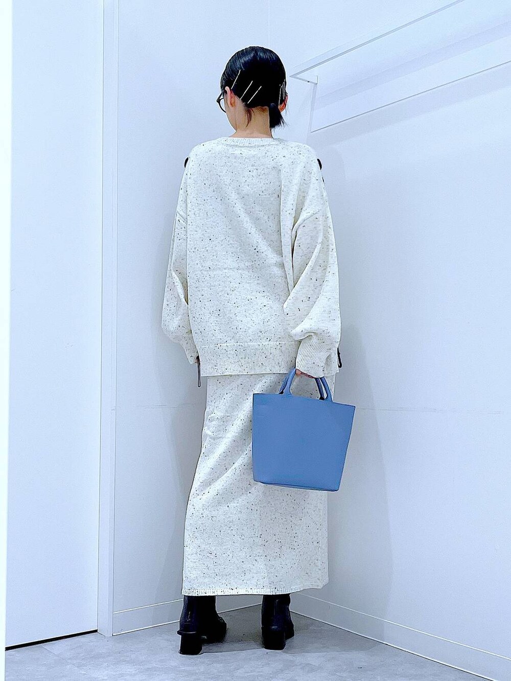 ブルー系のショルダーバッグ、ホワイト系のニット/セーター、ベージュ系のスカートを着用したレディースの秋コーディネートの5枚目の写真