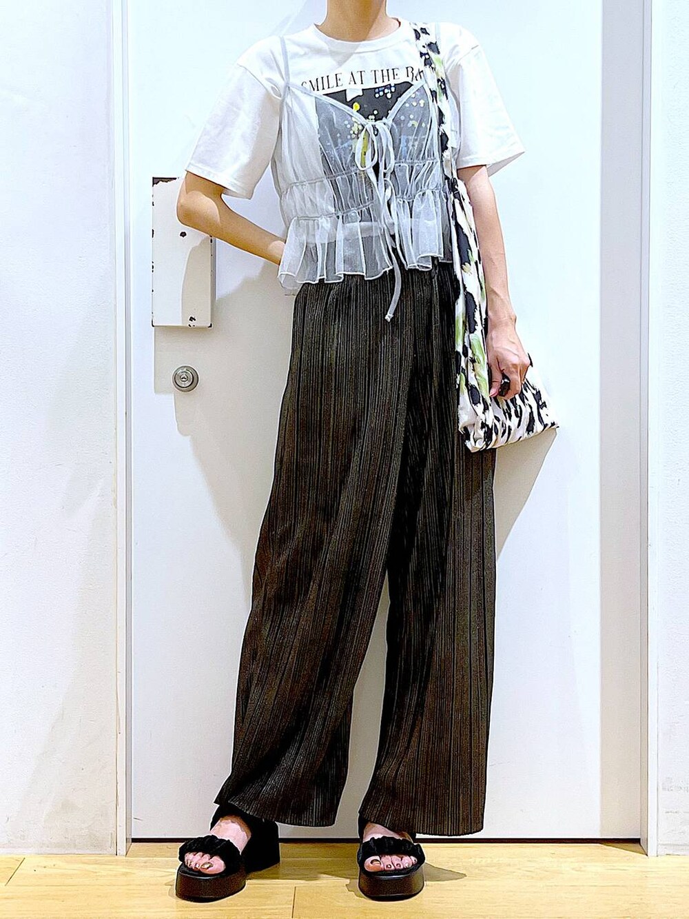 グリーン系のトートバッグ、シルバー系のキャミソール、ホワイト系のTシャツ/カットソーを着用したレディースの夏コーディネートの6枚目の写真