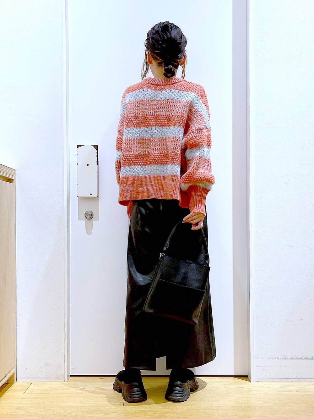 ブラック系のショルダーバッグ、ブラック系のブーツ、ブラック系のスカートを着用したレディースの冬コーディネートの5枚目の写真