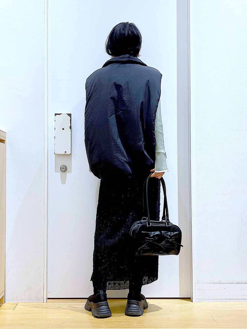 グリーン系のニット/セーター、ブラック系のハンドバッグ、ブラック系のブーツを着用したレディースの秋コーディネートの5枚目の写真