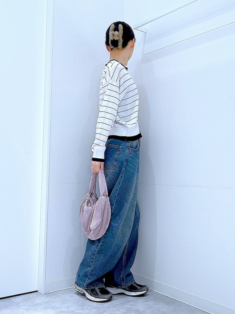 ブルー系のデニムパンツ、ピンク系のショルダーバッグ、ホワイト系のカーディガン/ボレロを着用したレディースの春コーディネートの4枚目の写真