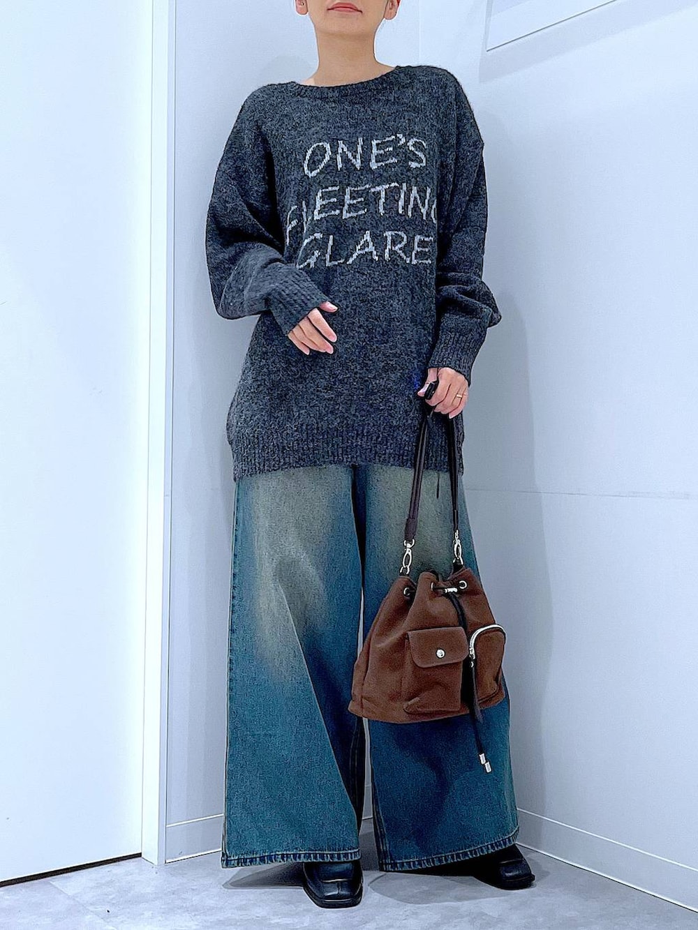 ブラウン系のショルダーバッグ、ブルー系のデニムパンツ、ブラック系のブーツを着用したレディースの冬コーディネートの6枚目の写真