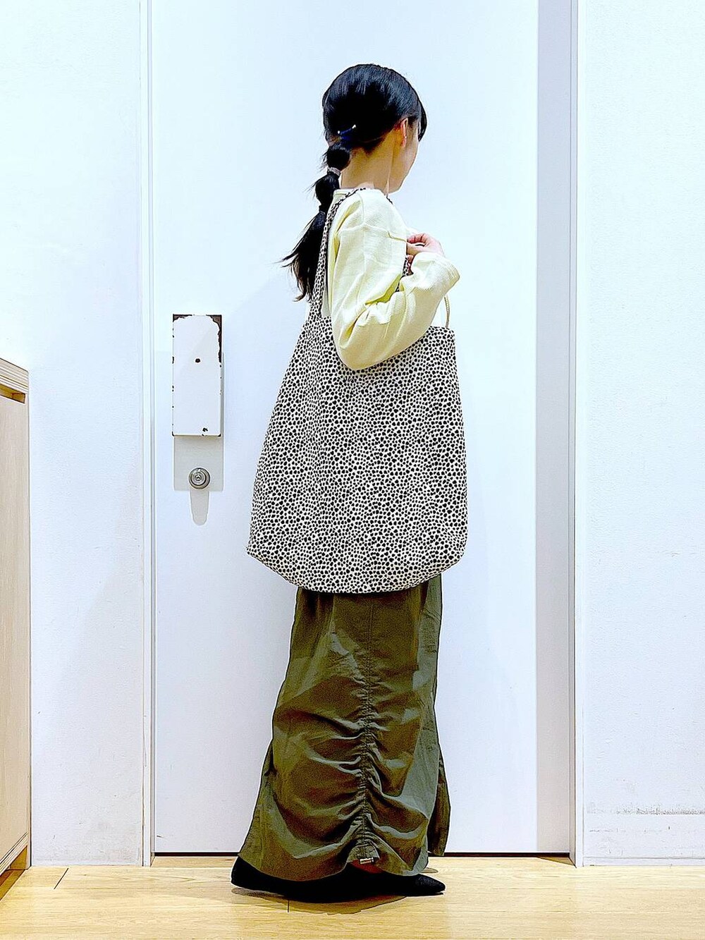 イエロー系のカーディガン/ボレロ、グリーン系のスカート、ベージュ系のトートバッグを着用したレディースの春コーディネートの4枚目の写真