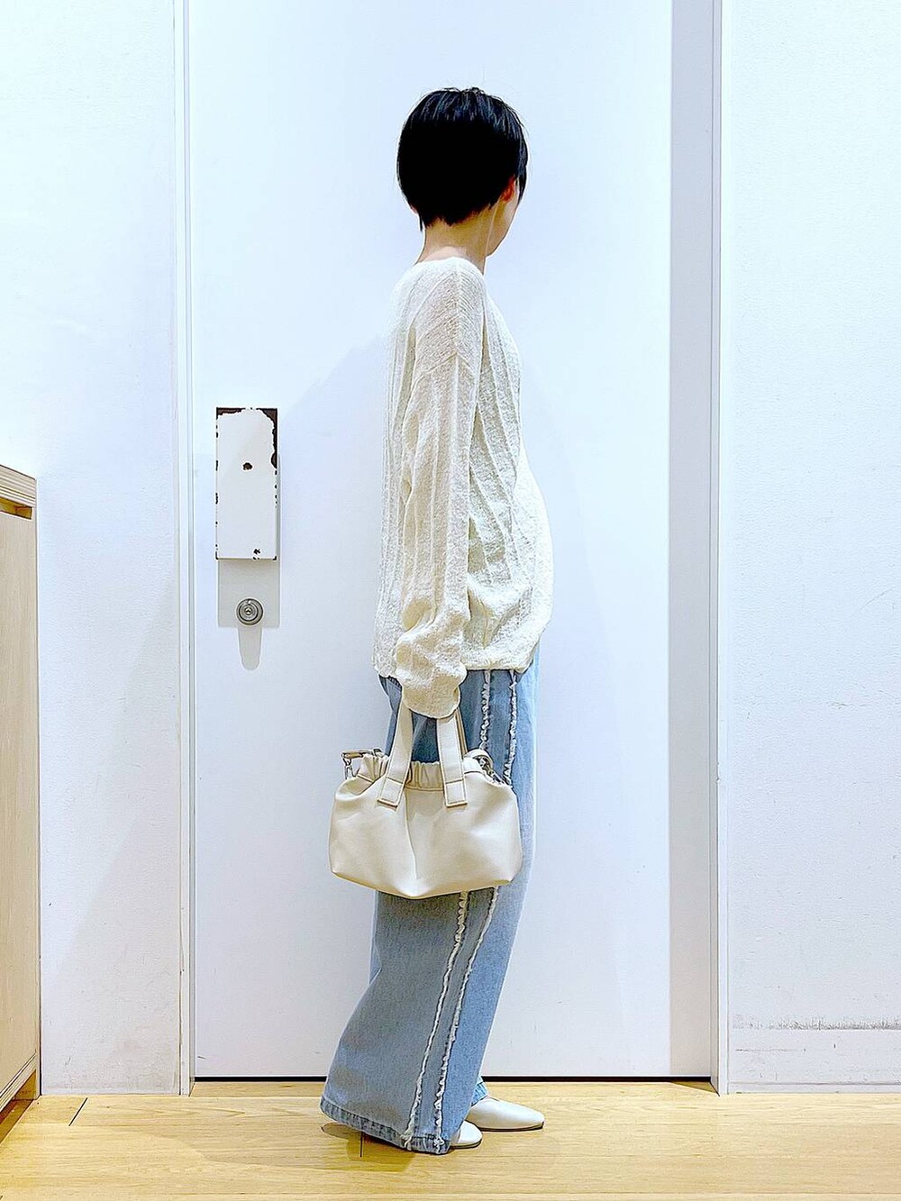 ホワイト系のショルダーバッグ、ホワイト系のパンプス、ブルー系のデニムパンツを着用したレディースの春コーディネートの4枚目の写真