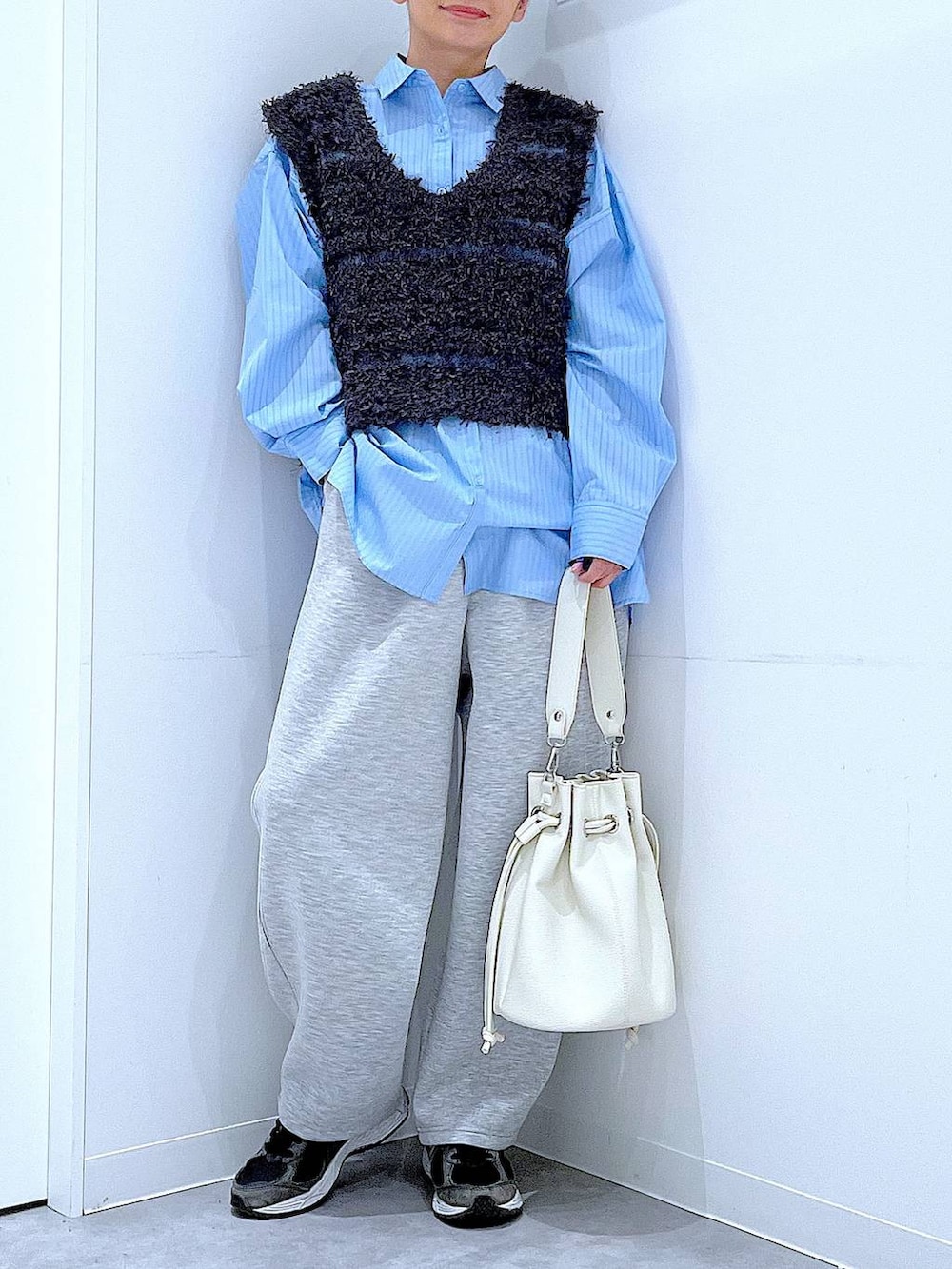 ブルー系のシャツ/ブラウス、ホワイト系のショルダーバッグ、グレー系のベストを着用したレディースの春コーディネートの6枚目の写真