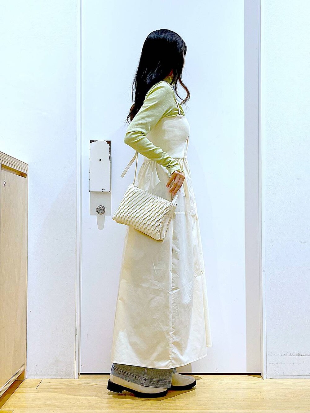 ホワイト系のショルダーバッグ、ベージュ系のブーツ、ブルー系のデニムパンツを着用したレディースの冬コーディネートの4枚目の写真