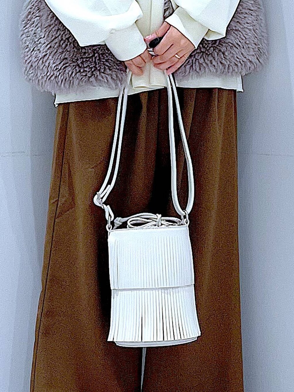 グレー系のベスト、ホワイト系のショルダーバッグ、ブラック系のブーツを着用したレディースの冬コーディネートの9枚目の写真