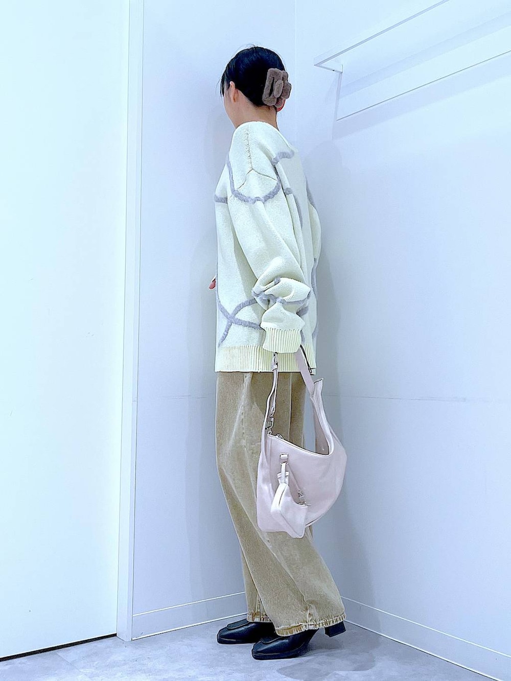 ベージュ系のデニムパンツ、ブラック系のブーツ、ホワイト系のショルダーバッグを着用したレディースの冬コーディネートの4枚目の写真