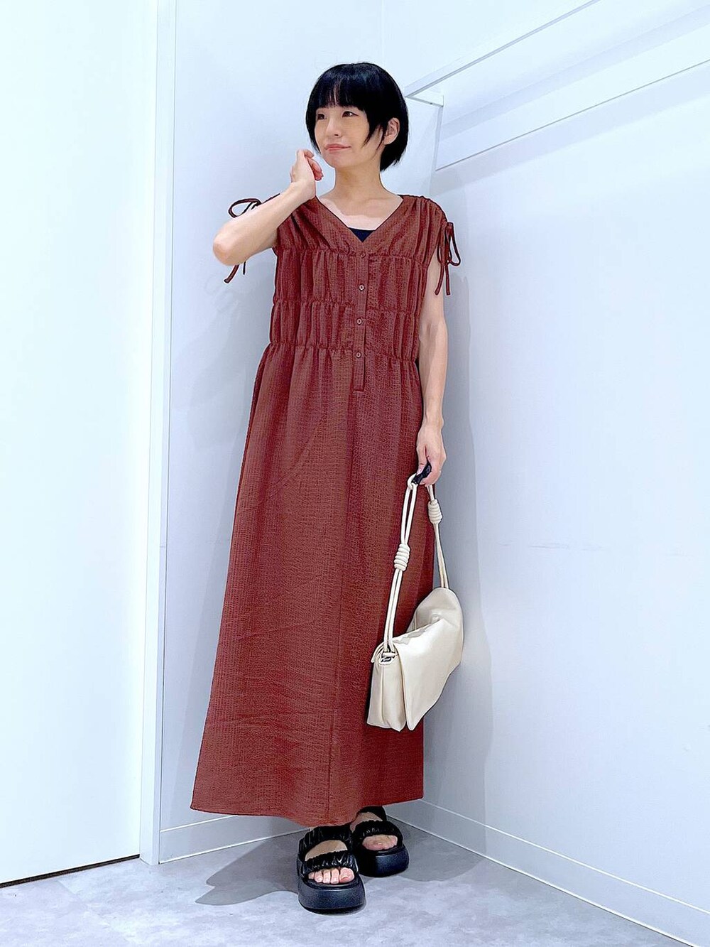 ブラック系のサンダル、ホワイト系のショルダーバッグ、ブラウン系のワンピースを着用したレディースの夏コーディネートの2枚目の写真