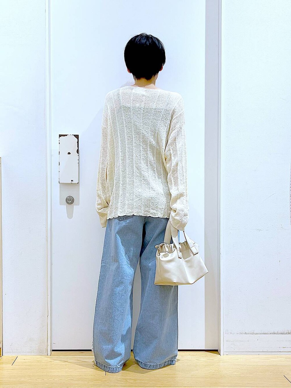 ホワイト系のショルダーバッグ、ホワイト系のパンプス、ブルー系のデニムパンツを着用したレディースの春コーディネートの5枚目の写真
