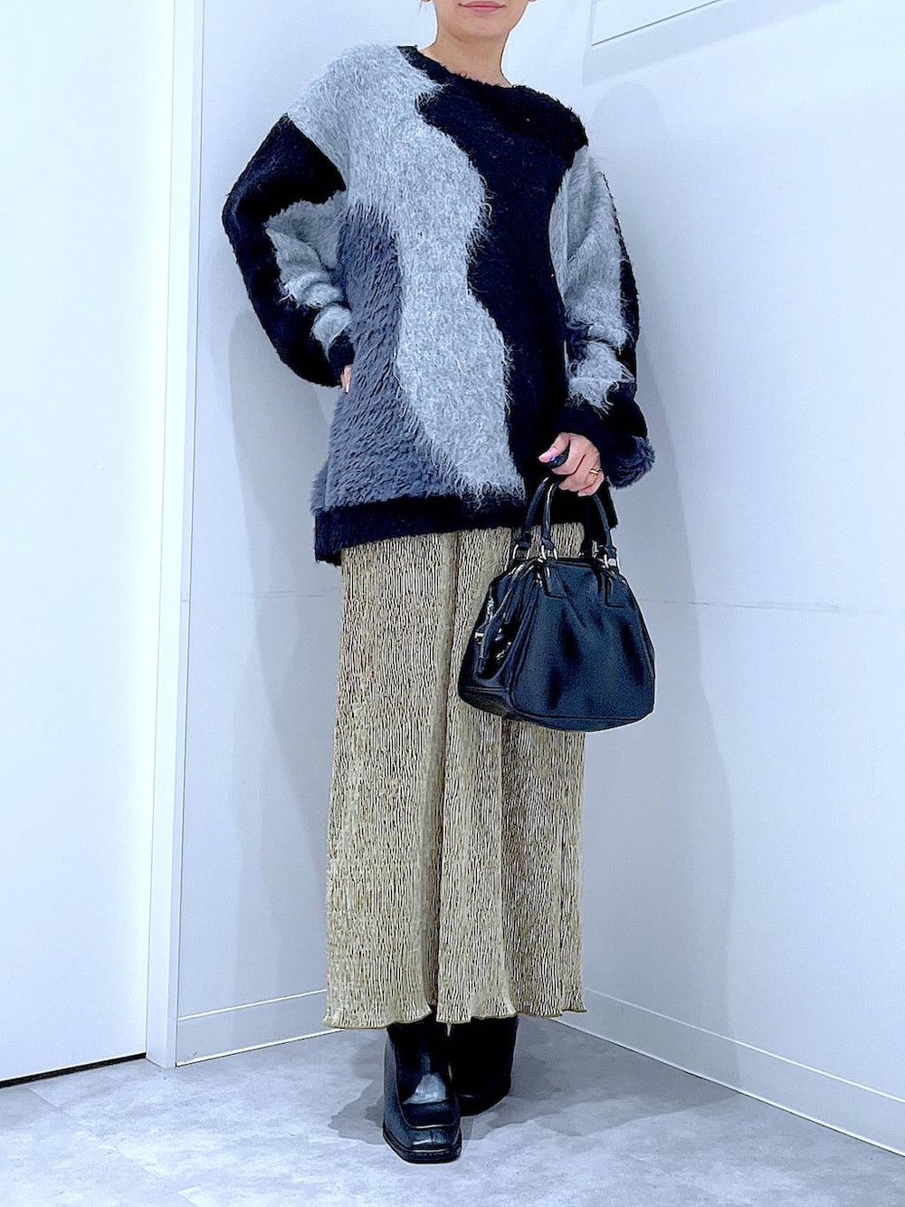 グレー系のニット/セーター、ブラック系のブーツ、ブラック系のショルダーバッグを着用したレディースの冬コーディネートの6枚目の写真