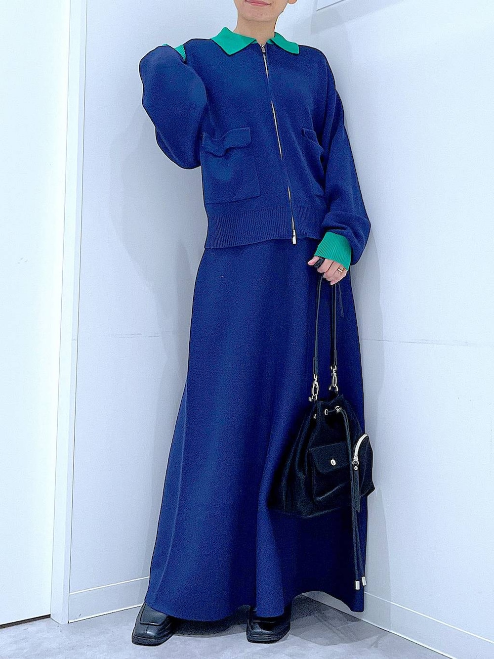 ブラック系のショルダーバッグ、ブラック系のブーツ、ブルー系のスカートを着用したレディースの冬コーディネートの6枚目の写真