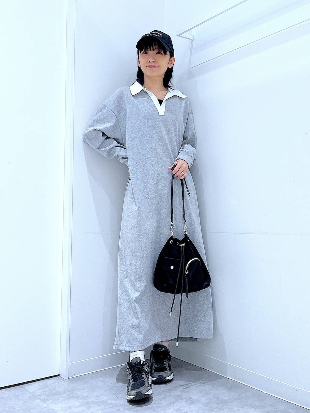 ブラック系のショルダーバッグ、グレー系のワンピース、ブラック系のキャップを着用したレディースの春コーディネートの2枚目の写真