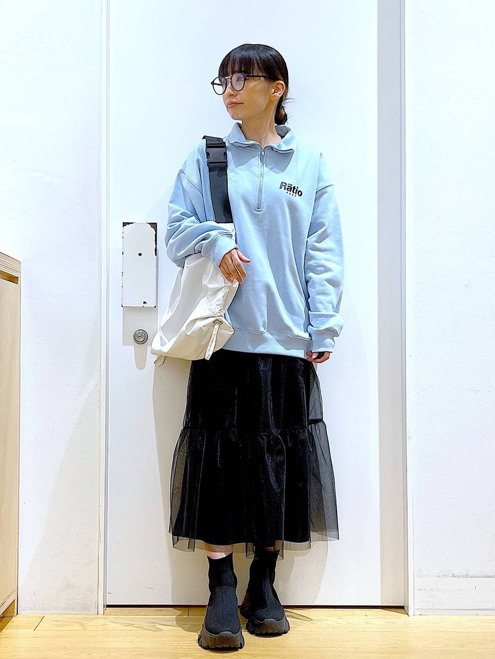 ブルー系のスウェット、ブラック系のブーツ、ホワイト系のショルダーバッグを着用したレディースの春コーディネートの2枚目の写真