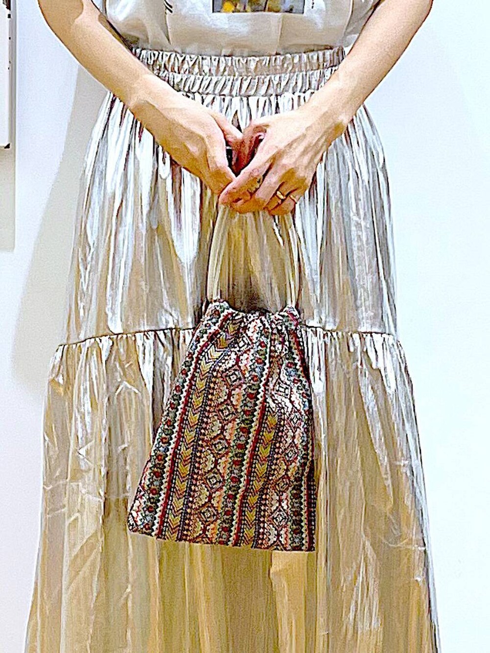 ピンク系のショルダーバッグ、シルバー系のスカート、ホワイト系のTシャツ/カットソーを着用したレディースの夏コーディネートの9枚目の写真