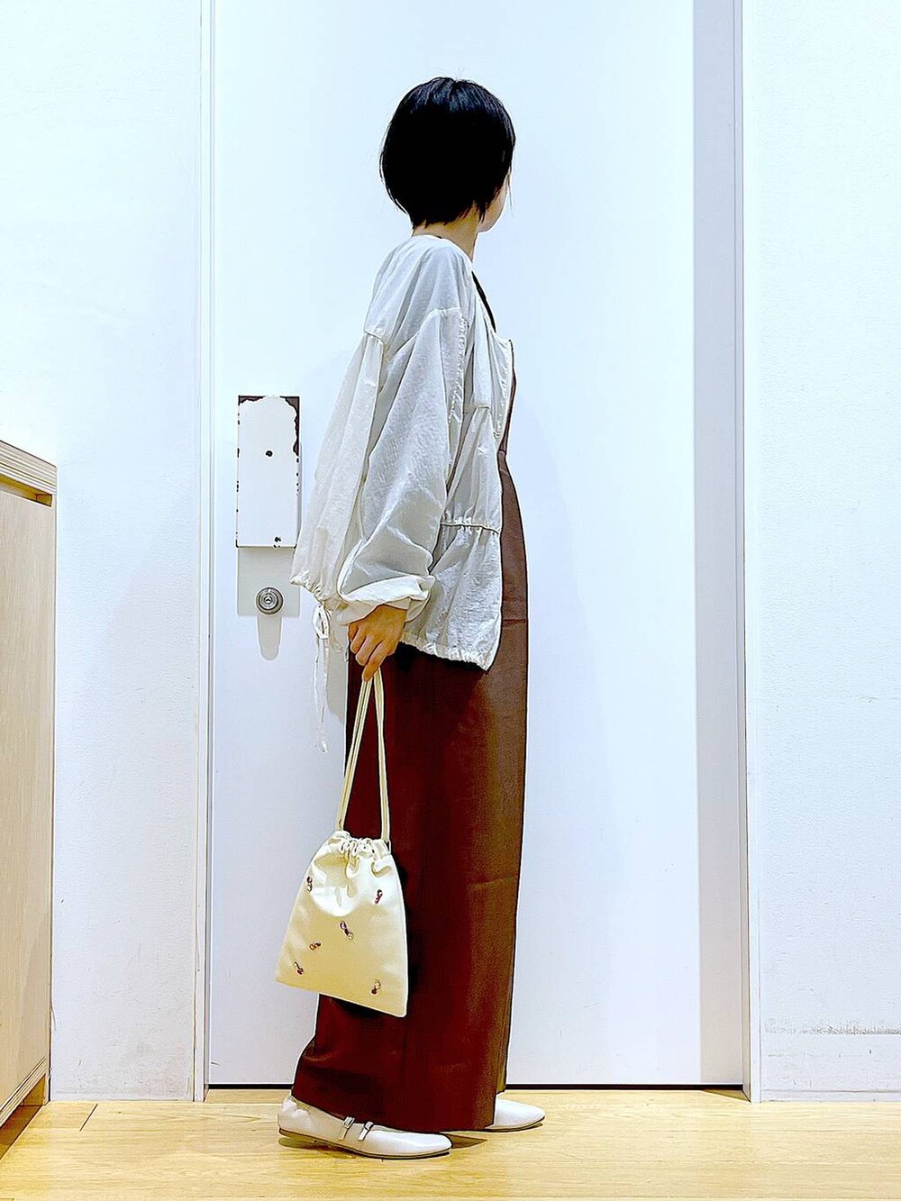 ホワイト系のショルダーバッグ、ホワイト系のパンプス、ブラック系のTシャツ/カットソーを着用したレディースの秋コーディネートの4枚目の写真