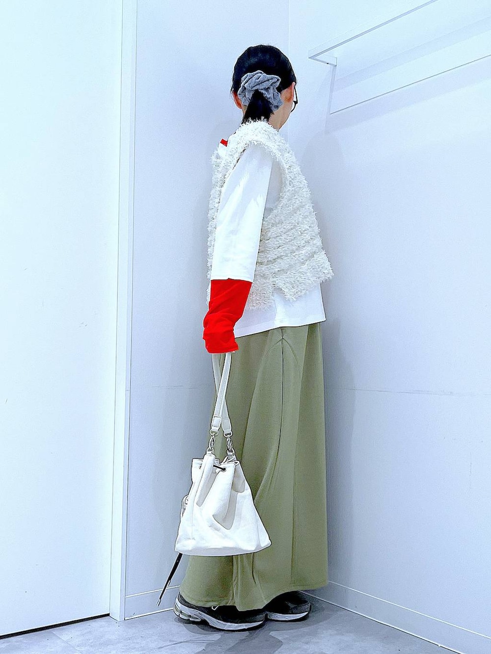 グリーン系のスカート、ホワイト系のTシャツ/カットソー、ベージュ系のベストを着用したレディースの冬コーディネートの4枚目の写真