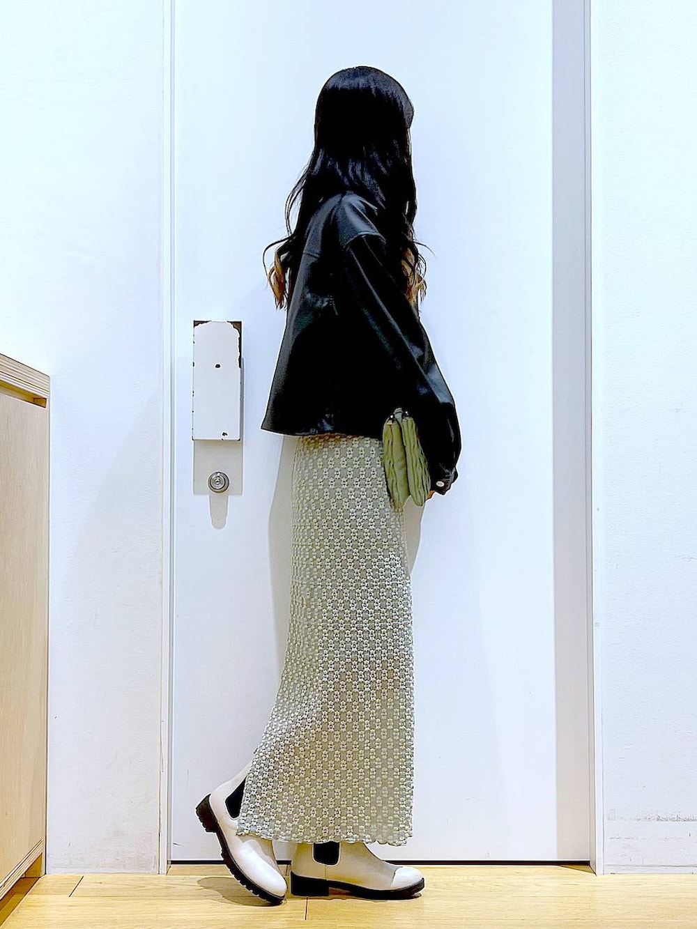 グリーン系のショルダーバッグ、ベージュ系のブーツ、グリーン系のスカートを着用したレディースの春コーディネートの4枚目の写真