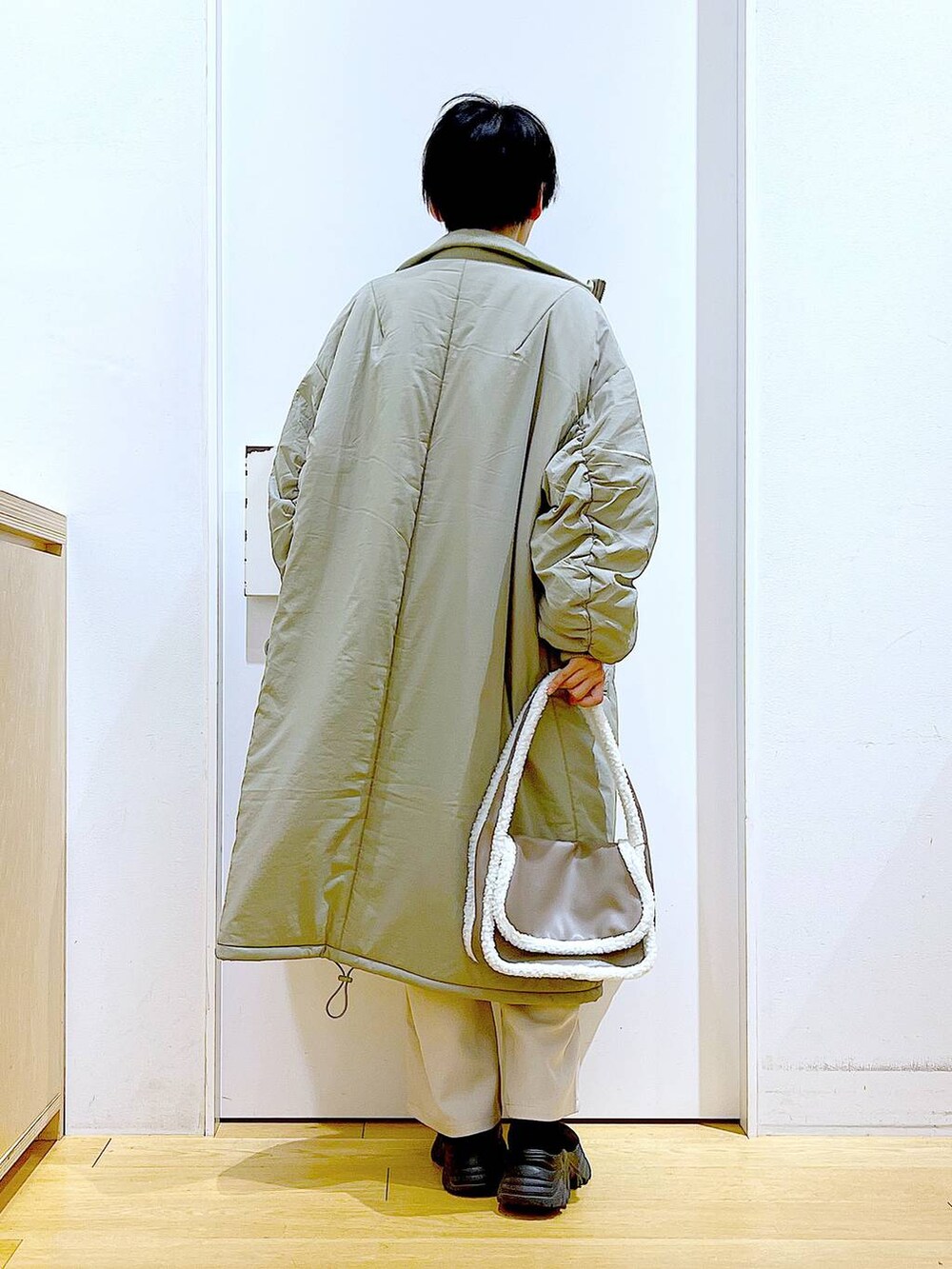 ブラック系のニット/セーター、ベージュ系のショルダーバッグ、ブラック系のブーツを着用したレディースの冬コーディネートの5枚目の写真