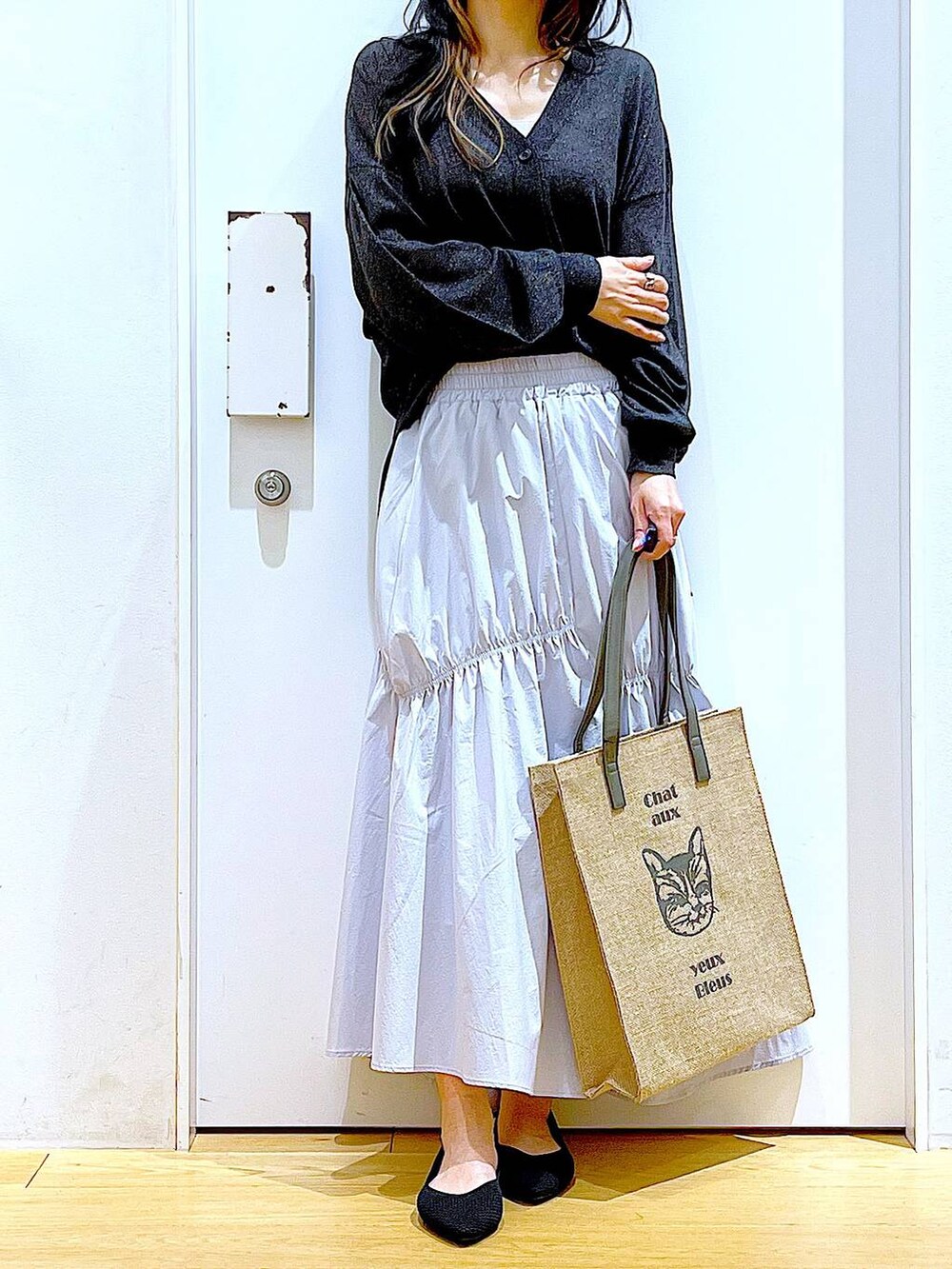 ブルー系のスカート、グレー系のカーディガン/ボレロ、ブラック系のパンプスを着用したレディースの春コーディネートの6枚目の写真