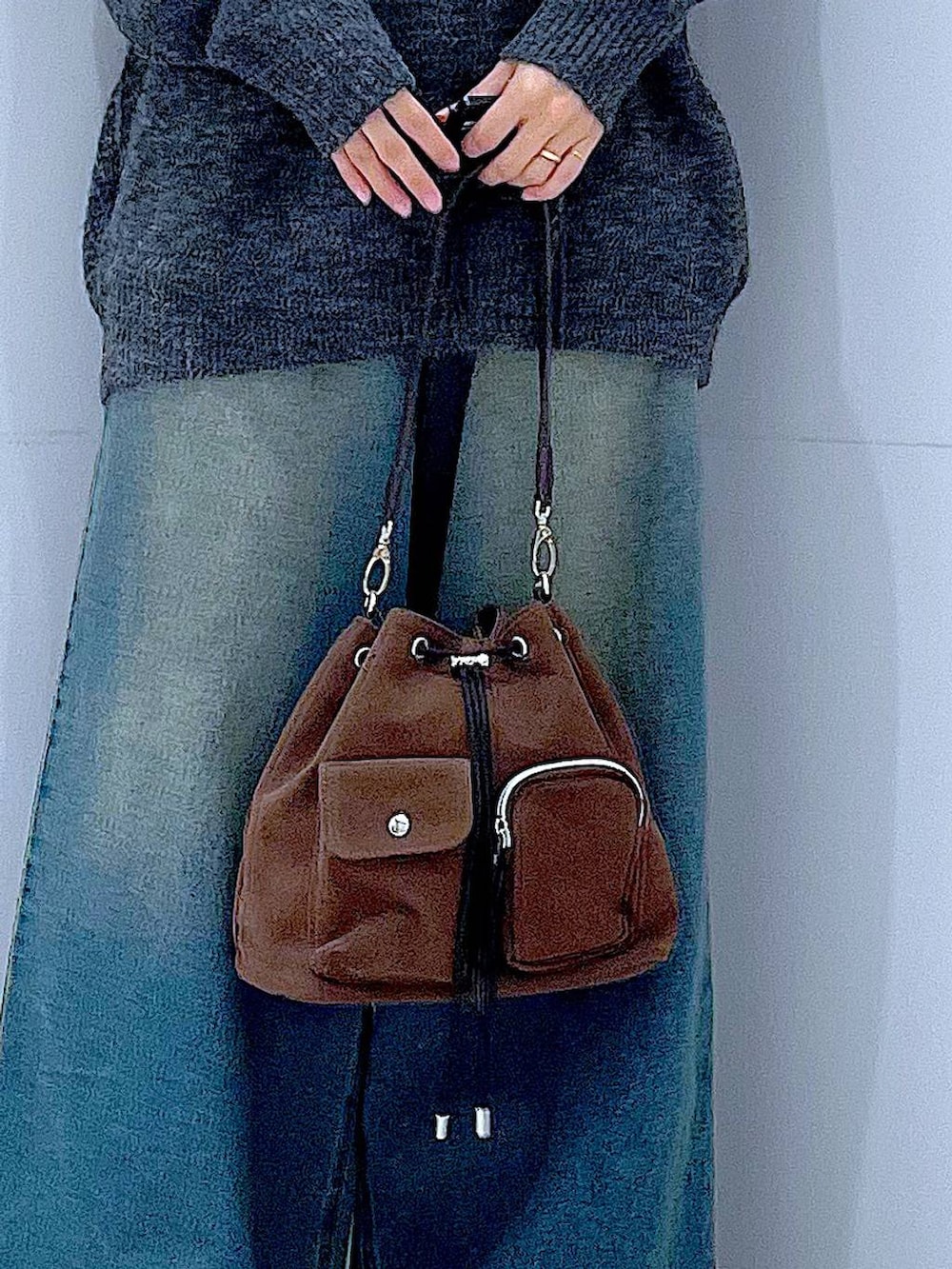 ブラウン系のショルダーバッグ、ブルー系のデニムパンツ、ブラック系のブーツを着用したレディースの冬コーディネートの9枚目の写真