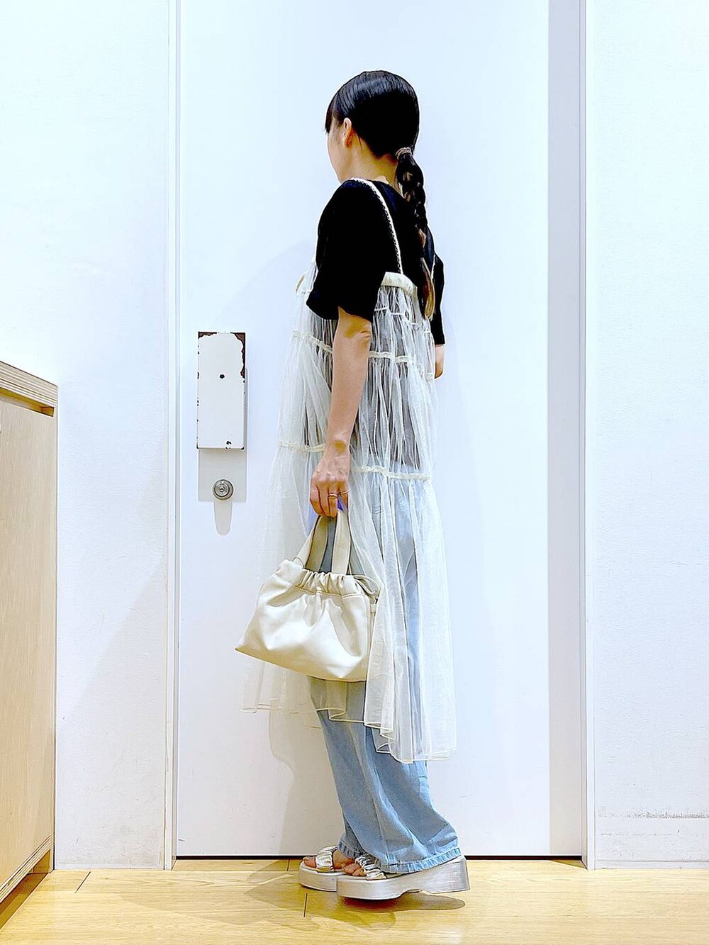 ブルー系のデニムパンツ、ホワイト系のショルダーバッグ、ブラック系のTシャツ/カットソーを着用したレディースの夏コーディネートの3枚目の写真