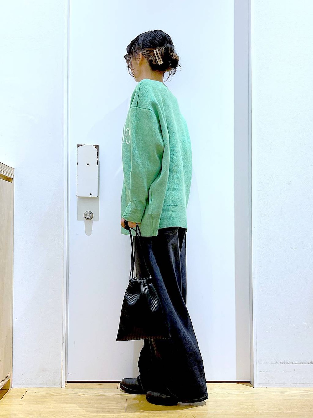 ブラック系のショルダーバッグ、ブラック系のブーツ、ブラック系のデニムパンツを着用したレディースの冬コーディネートの3枚目の写真