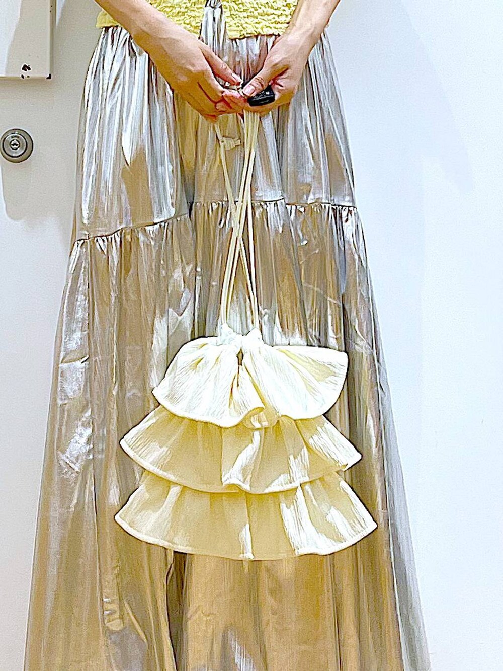 ホワイト系のサンダル、シルバー系のスカート、イエロー系のカーディガン/ボレロを着用したレディースの夏コーディネートの9枚目の写真