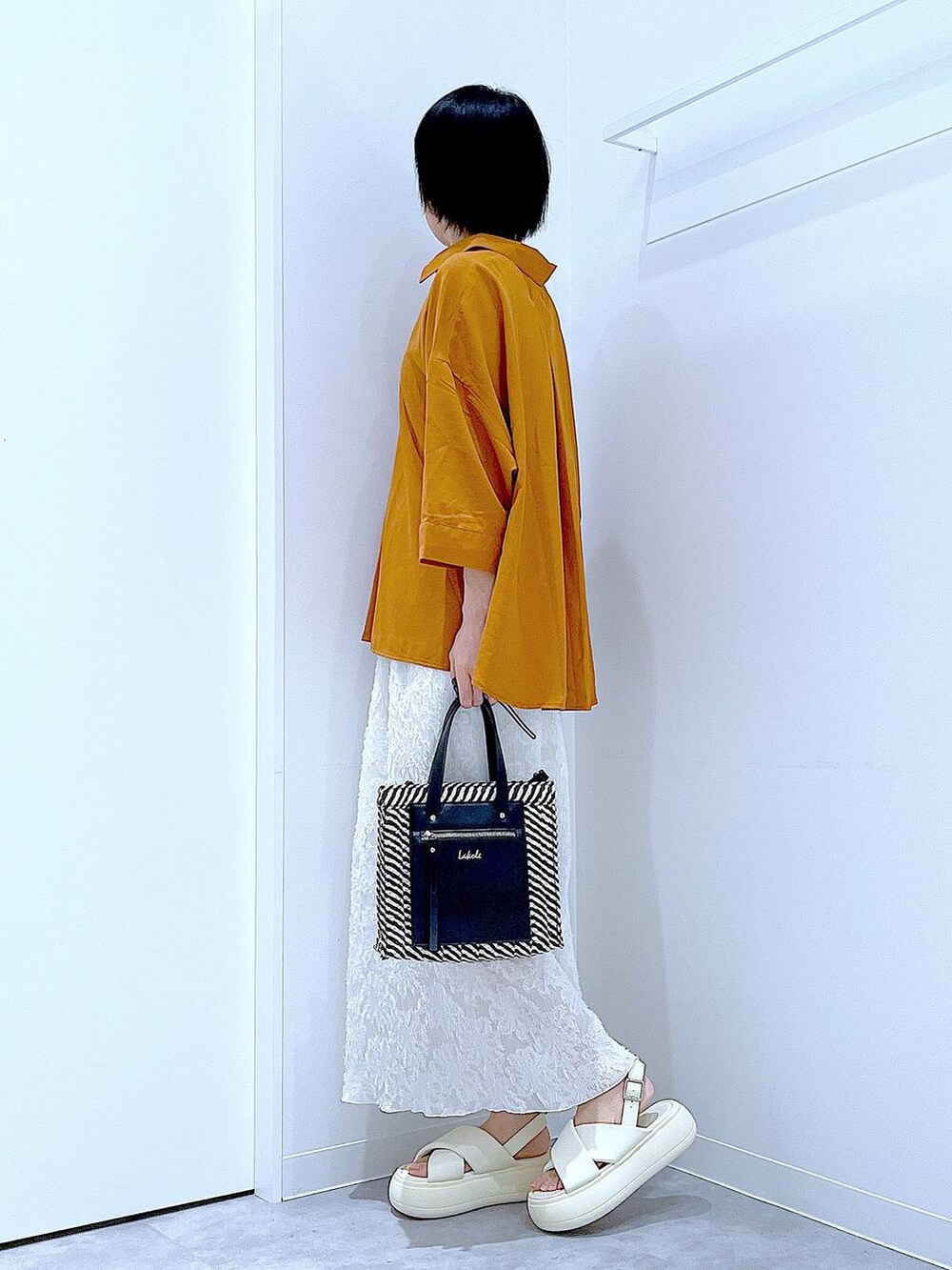 ブラック系のショルダーバッグ、ホワイト系のサンダル、ホワイト系のスカートを着用したレディースの夏コーディネートの3枚目の写真