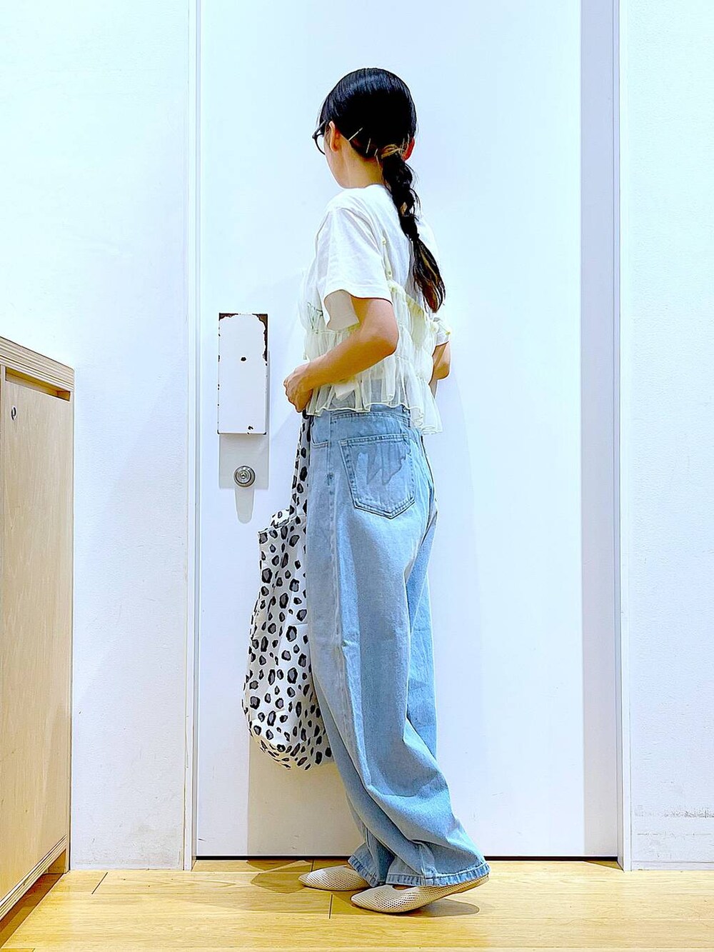 ブルー系のデニムパンツ、イエロー系のキャミソール、ホワイト系のトートバッグを着用したレディースの春コーディネートの3枚目の写真