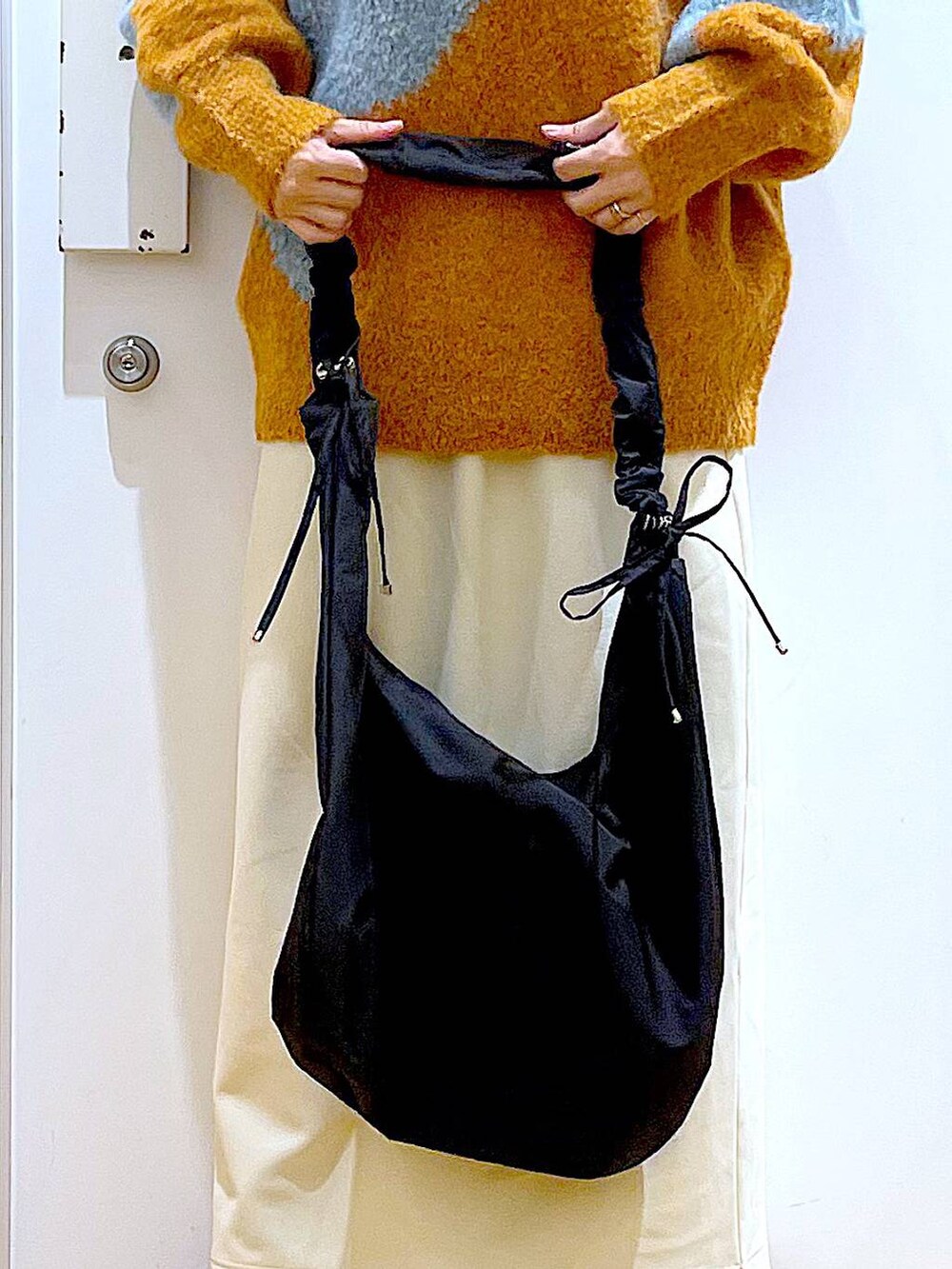 ブラック系のショルダーバッグ、ブラック系のブーツ、オレンジ系のニット/セーターを着用したレディースの冬コーディネートの9枚目の写真