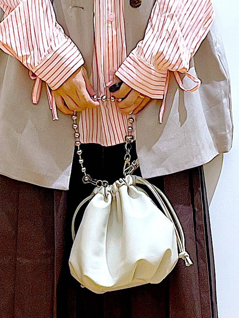 ベージュ系のショルダーバッグ、シルバー系のローファー、ベージュ系のベストを着用したレディースの秋コーディネートの9枚目の写真