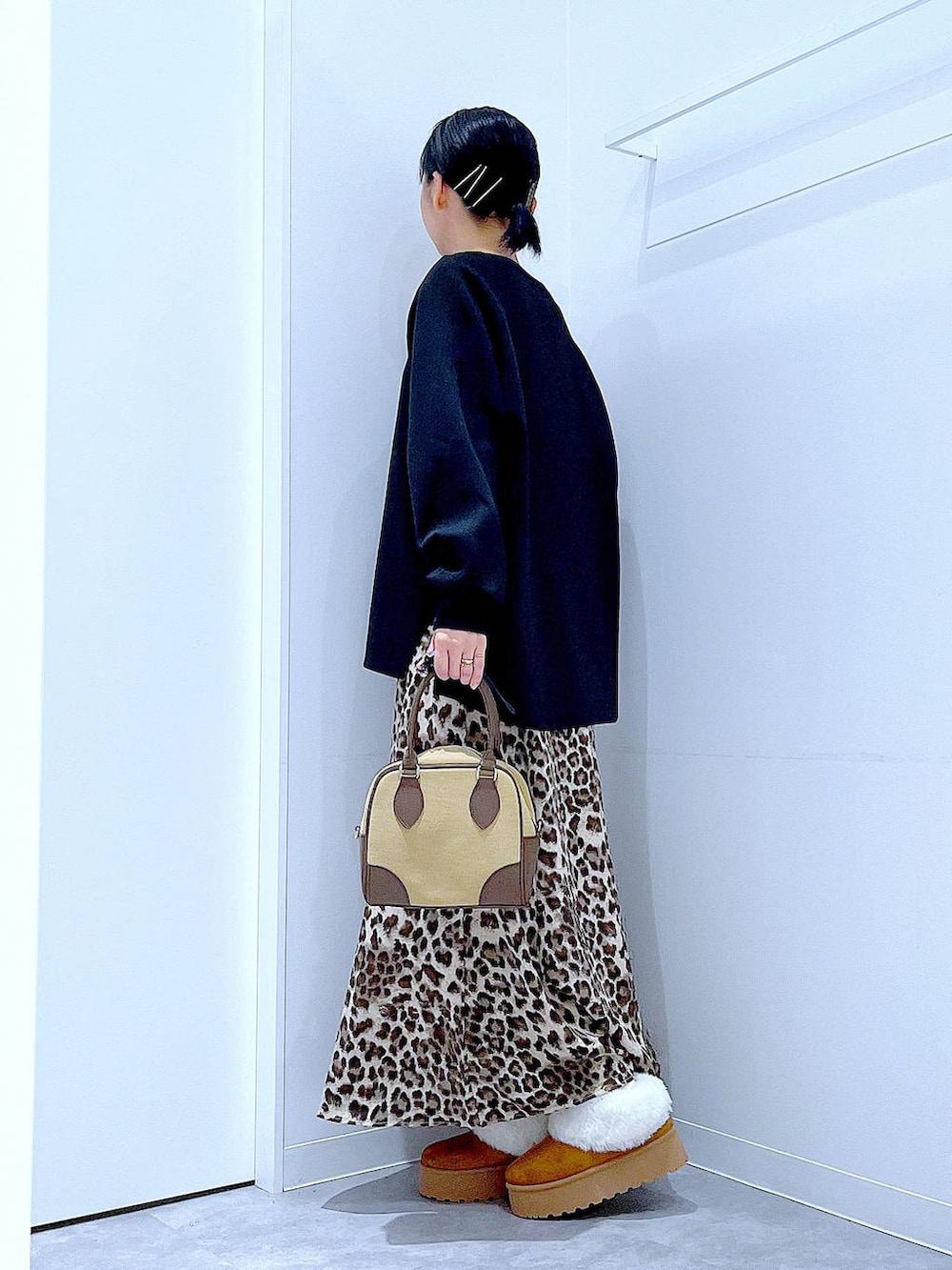 イエロー系のスリッポン、ベージュ系のハンドバッグ、ブラウン系のスカートを着用したレディースの秋コーディネートの3枚目の写真