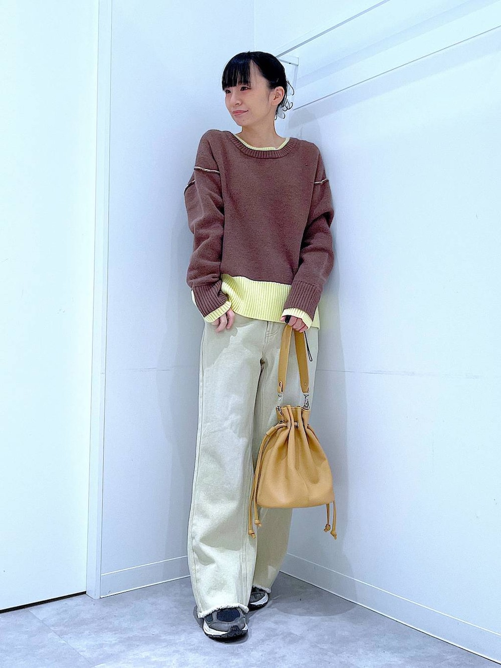 ブラウン系のニット/セーター、ベージュ系のデニムパンツ、ブラウン系のショルダーバッグを着用したレディースの冬コーディネートの2枚目の写真