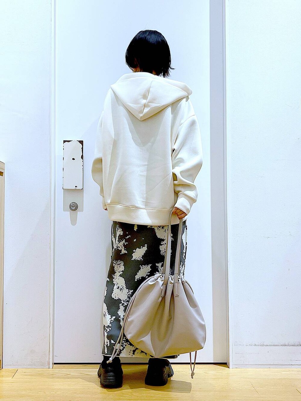 グレー系のスカート、ベージュ系のトートバッグ、ブラック系のブーツを着用したレディースの秋コーディネートの5枚目の写真