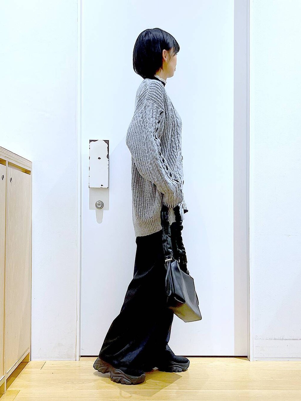 ブラック系のニット/セーター、ブラック系のブーツ、ブラック系のショルダーバッグを着用したレディースの冬コーディネートの4枚目の写真